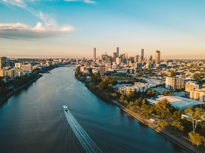 Sunset aerial shot of Brisbane as a City Cat heads towards the city on the Brisbane River