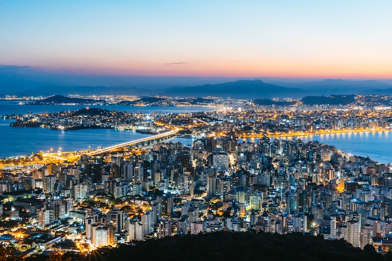 Aerial view of Florianópolis, Brazil, with high rise buildings and land extending out into the water.