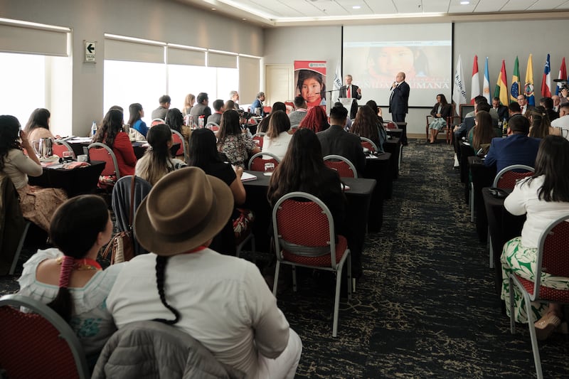 A hotel conference room is full of people seated and listening to Elder David A. Bednar at the El Roble Seminario Sudamericano conference in Lima, Peru.