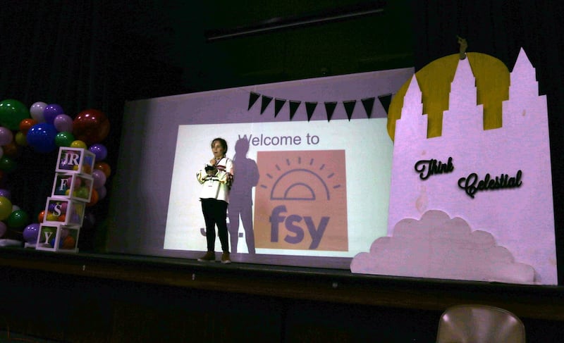 A leader on a stage with the words "Think Celestial" welcomes Primary children to a FSY-style day camp in Corpus Christi, Texas.