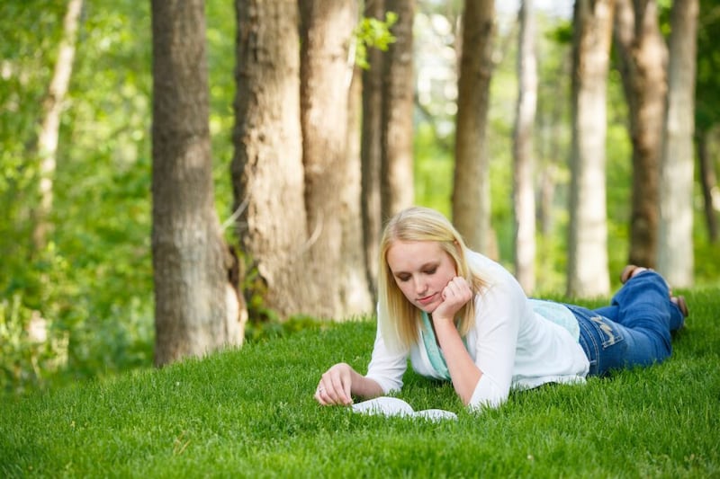 A young woman lying on the grass reads the scriptures. In the October 2020 general conference, President Russell M. Nelson invited all to make a list of God’s blessings to covenant Israel.
