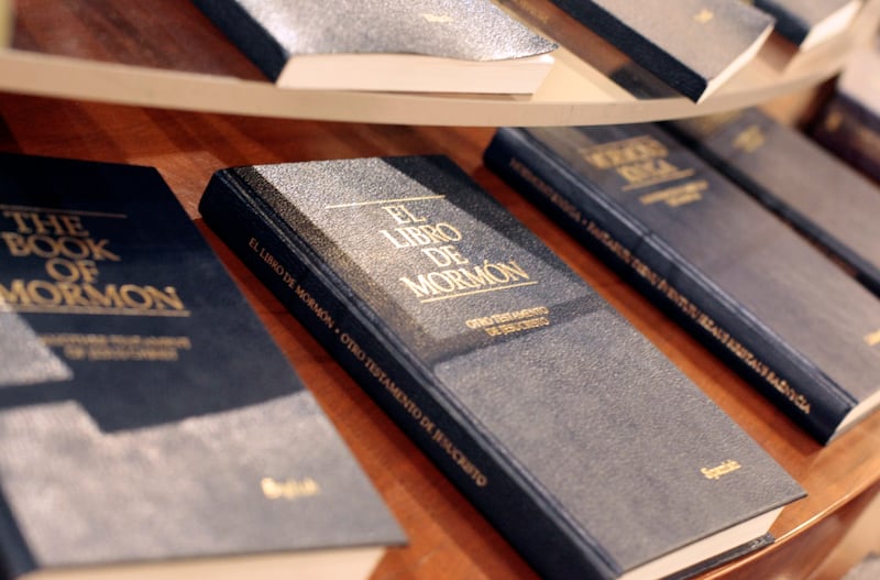 Blue hard-cover copies of the Book of Mormon on a table in English, Spanish and other languages