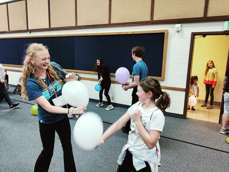 A youth counselor and child play with balloons at a stake Primary day camp in Corpus Christi, Texas.